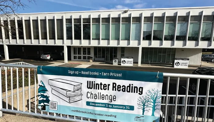 A winter reading banner hanging on the fence outside the library