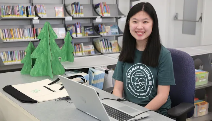 A summer high school volunteer at the summer reading desk